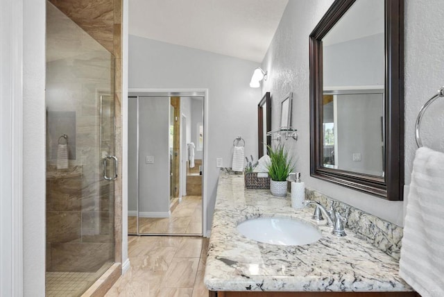 3442 Celinda Dr, Carlsbad, CA 92008 - bathroom with double vanity, marble look tile flooring, a shower stall, vaulted ceiling, and a textured wall
