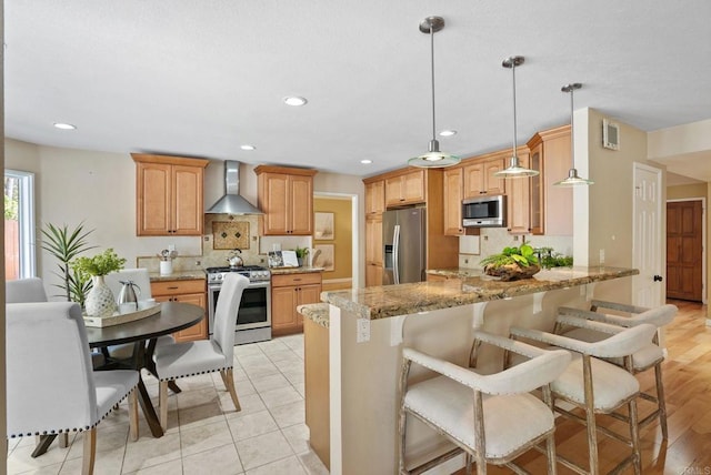 3442 Celinda Dr, Carlsbad, CA 92008 - kitchen featuring appliances with stainless steel finishes, wall chimney range hood, a peninsula, light stone countertops, and recessed lighting