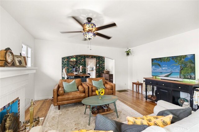 206 S Wisconsin St, Fallbrook, CA 92028 - living room featuring ceiling fan, wood finished floors, a brick fireplace, baseboards, and arched walkways