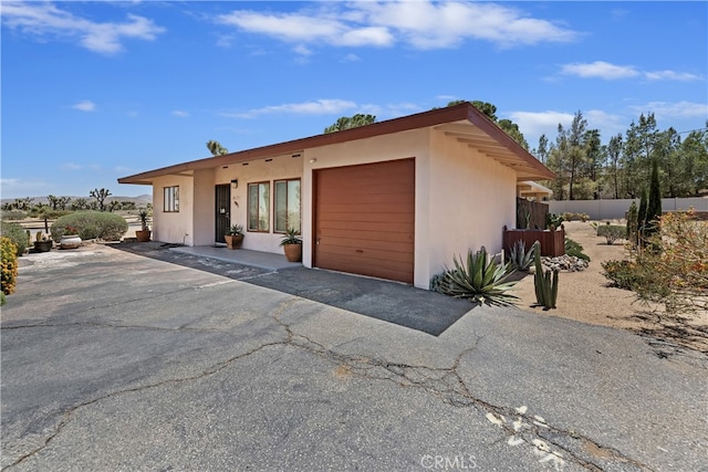 56287 Navajo Trl, Yucca Valley, CA 92284 - view of front of property featuring stucco siding, an attached garage, and asphalt driveway