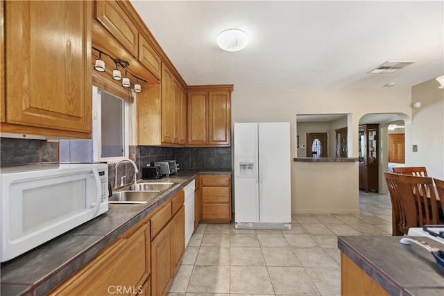 56287 Navajo Trl, Yucca Valley, CA 92284 - kitchen featuring white appliances, a sink, backsplash, dark countertops, and arched walkways