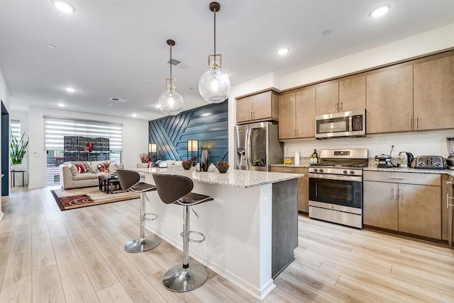 5261 Beachfront Cove St # 174, San Diego, CA 92154 - kitchen featuring stainless steel appliances, open floor plan, light wood-style floors, light stone counters, and recessed lighting