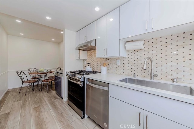 28012 Ridgeforest Ct, Rancho Palos Verdes, CA 90275 - kitchen with stainless steel appliances, under cabinet range hood, light countertops, white cabinets, and tasteful backsplash