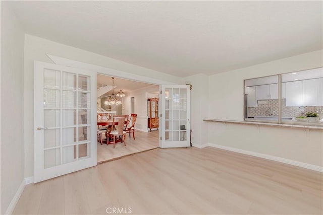 28012 Ridgeforest Ct, Rancho Palos Verdes, CA 90275 - unfurnished living room with light wood-style floors, a chandelier, baseboards, and french doors