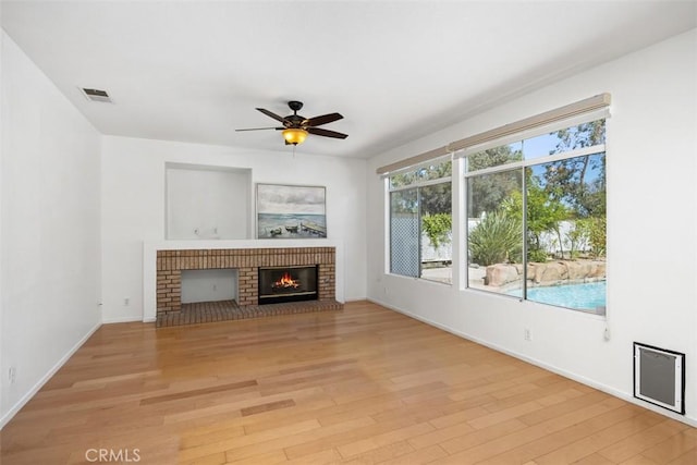 32147 Corte Florecita, Temecula, CA 92592 - unfurnished living room featuring a brick fireplace, light wood-style flooring, baseboards, and a ceiling fan