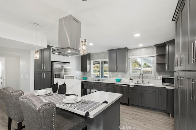 25781 Interlechen Dr, Menifee, CA 92586 - kitchen featuring island range hood, appliances with stainless steel finishes, a sink, light wood-style flooring, and tasteful backsplash