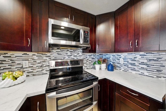 3078 Broadway Unit 210, San Diego, CA 92102 - kitchen featuring appliances with stainless steel finishes, backsplash, light stone countertops, and reddish brown cabinets