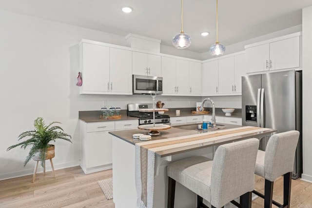 35180 Grove Trl, Fallbrook, CA 92028 - kitchen with appliances with stainless steel finishes, a sink, light wood-style flooring, hanging light fixtures, and a breakfast bar area