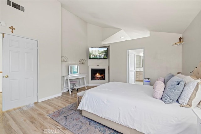 3314 Sandstone Ct, Palmdale, CA 93551 - bedroom with wood finished floors, a warm lit fireplace, baseboards, ensuite bath, and high vaulted ceiling