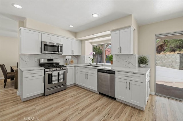 3314 Sandstone Ct, Palmdale, CA 93551 - kitchen with stainless steel appliances, a sink, light wood finished floors, white cabinetry, and tasteful backsplash