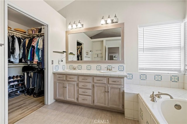 3314 Sandstone Ct, Palmdale, CA 93551 - bathroom featuring double vanity, a garden tub, wood finished floors, and a walk in closet