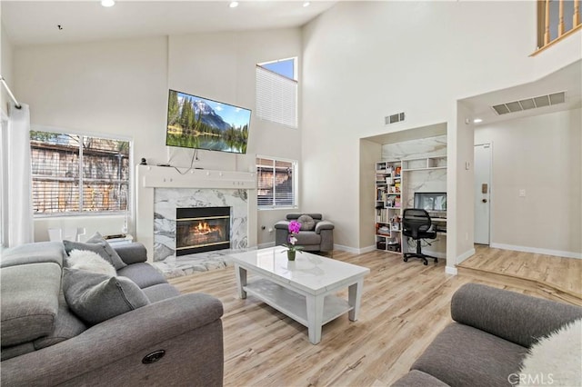 3314 Sandstone Ct, Palmdale, CA 93551 - living room featuring an office area, a towering ceiling, light wood finished floors, plenty of natural light, and a high end fireplace