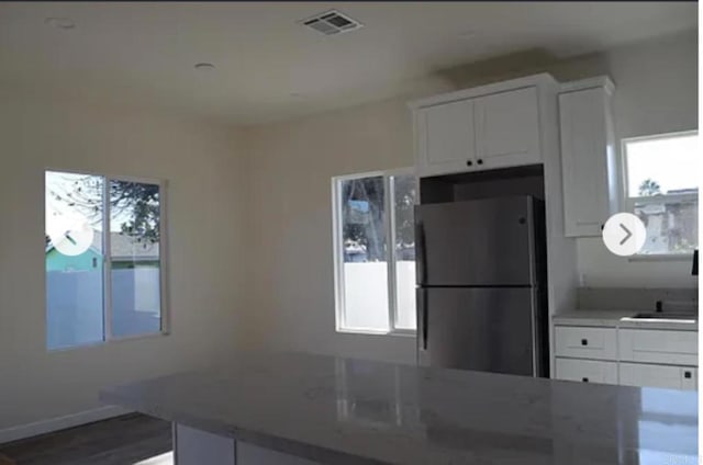 12426 Oaklawn Ave, Chula Vista, CA 91910 - kitchen with freestanding refrigerator, white cabinetry, wood finished floors, and light stone counters
