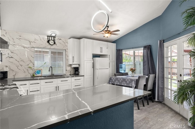 24457 Liolios Way, Moreno Valley, CA 92551 - kitchen with freestanding refrigerator, a sink, vaulted ceiling, white cabinetry, and light wood-style flooring