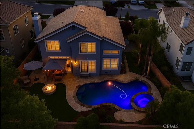 27324 Chesterfield Dr, Valencia, CA 91354 - back of house at twilight with a patio area, stucco siding, a fenced backyard, a pool with connected hot tub, and an outdoor fire pit