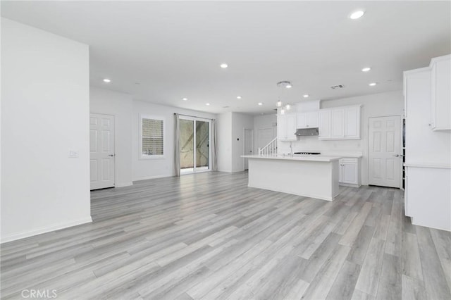 7453 Jersey St, Chino, CA 91708 - kitchen with under cabinet range hood, open floor plan, recessed lighting, white cabinetry, and light countertops