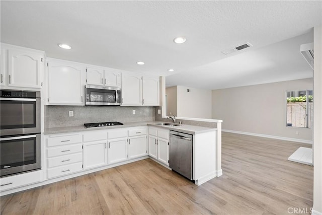 3 Andria, Irvine, CA 92614 - kitchen with appliances with stainless steel finishes, a peninsula, a sink, white cabinetry, and light wood finished floors