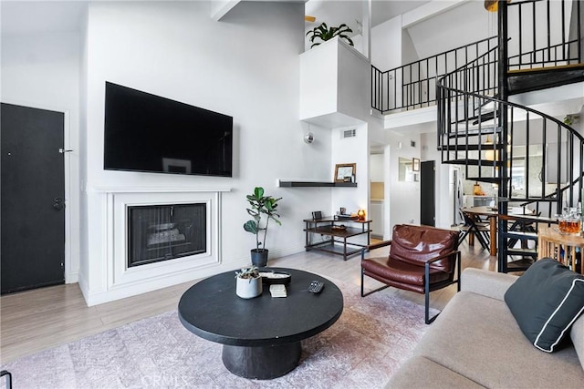 26873 Claudette St Unit 112, Canyon Country, CA 91351 - living area with stairs, wood finished floors, a towering ceiling, baseboards, and a glass covered fireplace