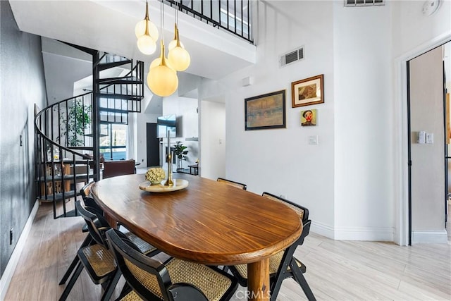 26873 Claudette St Unit 112, Canyon Country, CA 91351 - dining area featuring stairway, a high ceiling, baseboards, and light wood finished floors