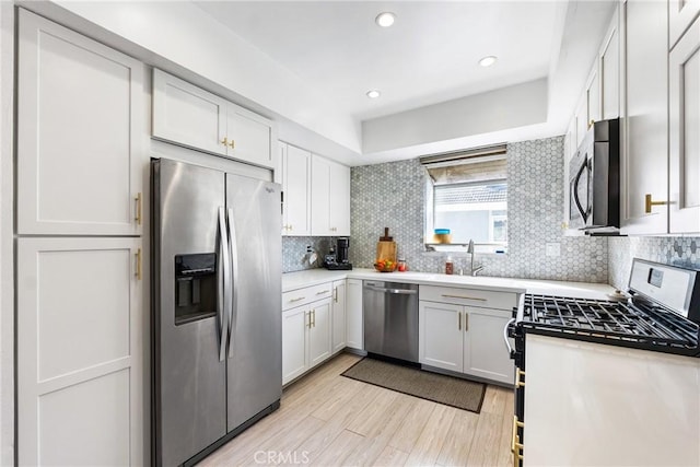 26873 Claudette St Unit 112, Canyon Country, CA 91351 - kitchen with appliances with stainless steel finishes, light wood-style flooring, a sink, tasteful backsplash, and light countertops