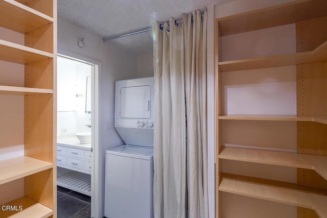 631 Wilcox Ave Unit 2E, Los Angeles, CA 90004 - laundry room featuring stacked washing machine and dryer, a textured ceiling, and dark tile patterned floors