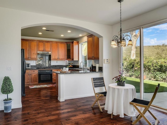 11615 Trailbrook Ln, San Diego, CA 92128 - kitchen featuring black appliances, brown cabinets, arched walkways, dark wood finished floors, and a peninsula
