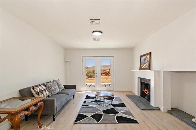 9255 Fortuna Ave, Yucca Valley, CA 92284 - living area with light wood-style flooring, a warm lit fireplace, and french doors