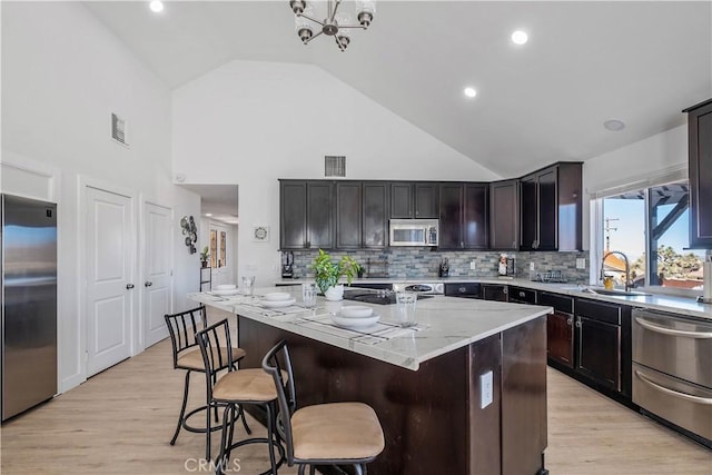 9255 Fortuna Ave, Yucca Valley, CA 92284 - kitchen featuring appliances with stainless steel finishes, a sink, high vaulted ceiling, a center island, and light wood-type flooring