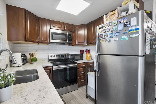 1450 Melrose Ave Unit 25, Chula Vista, CA 91911 - kitchen with stainless steel appliances, a sink, tasteful backsplash, light wood finished floors, and light stone counters