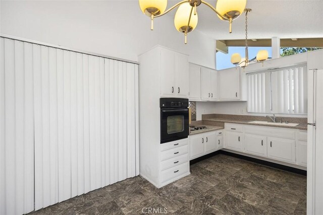 542 Via Estrada Unit A, Laguna Woods, CA 92637 - kitchen with black oven, a sink, white cabinets, lofted ceiling, and stovetop