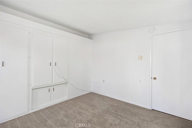 542 Via Estrada Unit A, Laguna Woods, CA 92637 - unfurnished bedroom featuring carpet flooring, a closet, and a textured ceiling