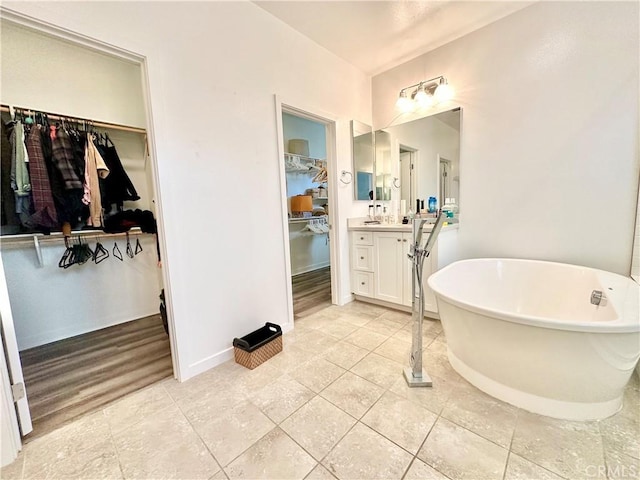 403 Aura Dr, Costa Mesa, CA 92626 - bathroom with a freestanding tub, a spacious closet, vanity, tile patterned floors, and baseboards