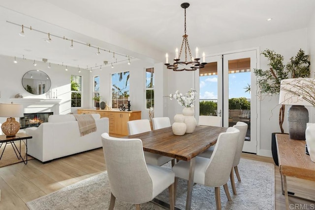 2386 Lapis Rd, Carlsbad, CA 92009 - dining space featuring a chandelier, healthy amount of natural light, light wood-style floors, and a glass covered fireplace