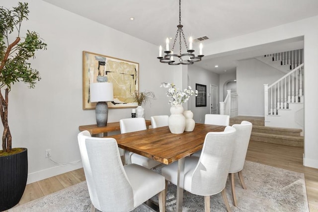 2386 Lapis Rd, Carlsbad, CA 92009 - dining space with a chandelier, stairway, light wood-style flooring, arched walkways, and baseboards