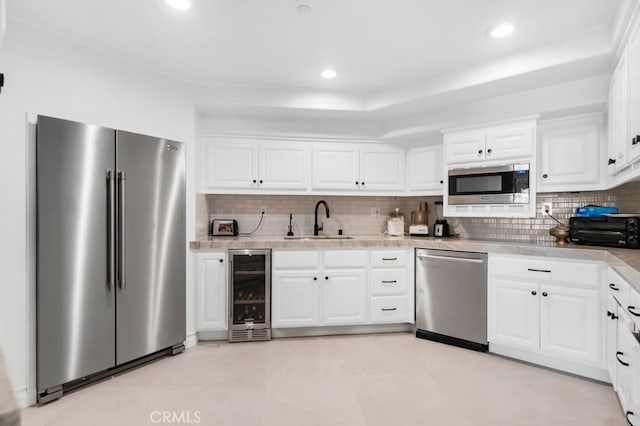 8 Saint Tropez, Laguna Niguel, CA 92677 - kitchen with appliances with stainless steel finishes, beverage cooler, a sink, decorative backsplash, and white cabinets
