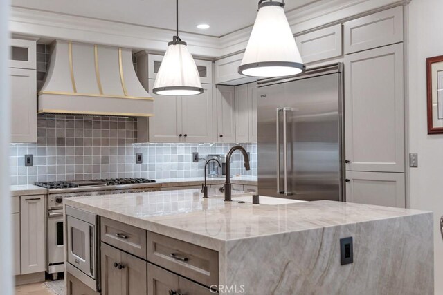 8 Saint Tropez, Laguna Niguel, CA 92677 - kitchen with premium appliances, custom range hood, decorative backsplash, a kitchen island with sink, and light stone counters