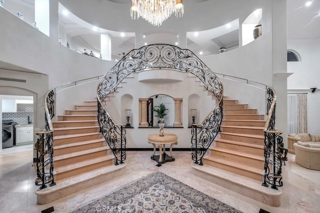 8 Saint Tropez, Laguna Niguel, CA 92677 - staircase featuring a high ceiling, a chandelier, marble tiled floors, washer / clothes dryer, and arched walkways