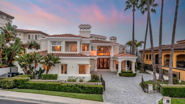 8 Saint Tropez, Laguna Niguel, CA 92677 - mediterranean / spanish house featuring a tiled roof, decorative driveway, a chimney, stucco siding, and a balcony