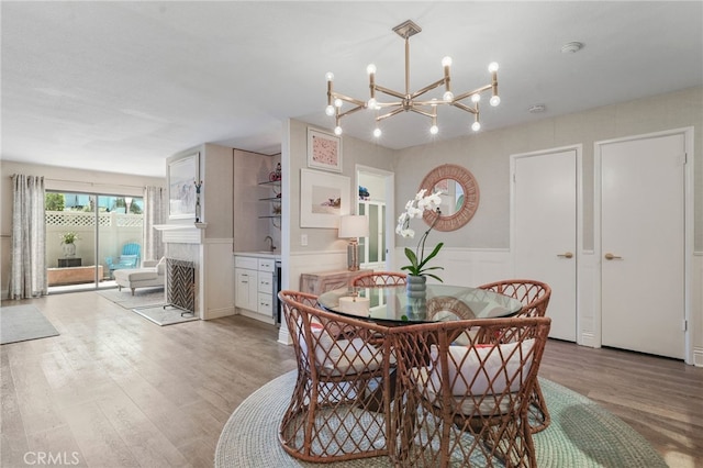 700 Esplanade Unit 9, Redondo Beach, CA 90277 - dining space featuring light wood-style flooring, a fireplace, a chandelier, a decorative wall, and wainscoting