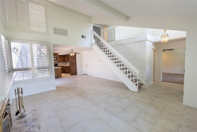 1903 W W Wind, Santa Ana, CA 92704 - unfurnished living room featuring a towering ceiling, stairs, ceiling fan, beam ceiling, and a chandelier
