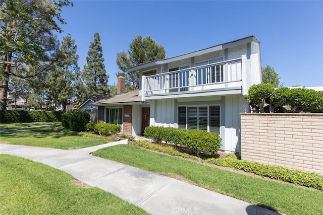 1903 W W Wind, Santa Ana, CA 92704 - view of front facade featuring a balcony, a front yard, stucco siding, and a chimney