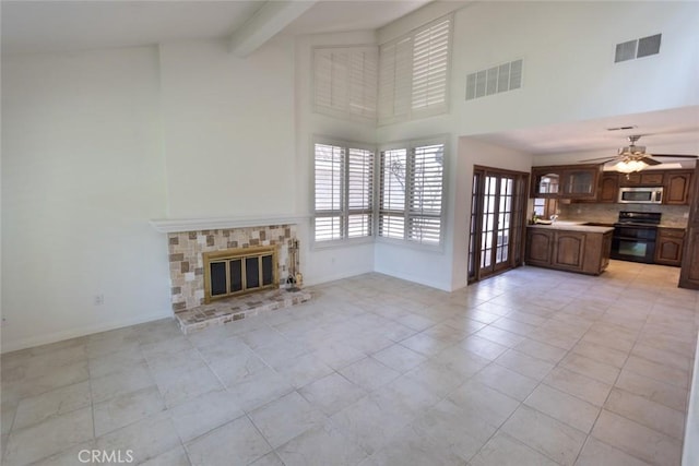 1903 W W Wind, Santa Ana, CA 92704 - unfurnished living room with a towering ceiling, baseboards, a brick fireplace, a ceiling fan, and light tile patterned floors