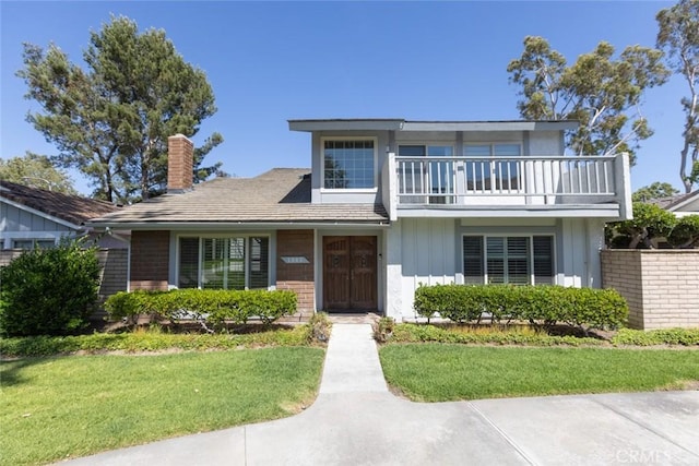 1903 W W Wind, Santa Ana, CA 92704 - view of front of home with a balcony, a front yard, a chimney, and board and batten siding