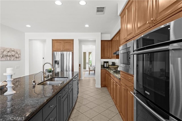 26865 Grey Pl, Stevenson Ranch, CA 91381 - kitchen featuring stainless steel appliances, a sink, light tile patterned flooring, dark stone counters, and brown cabinets