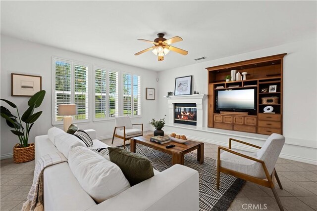26865 Grey Pl, Stevenson Ranch, CA 91381 - living room with tile patterned floors, a ceiling fan, baseboards, and a glass covered fireplace