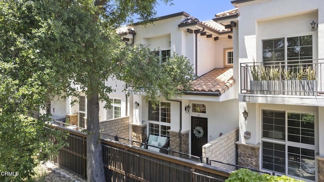3236 Royal Oaks Dr Unit 5, Thousand Oaks, CA 91362 - view of front of home with a tiled roof, stucco siding, a balcony, and stone siding