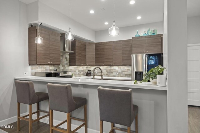 3236 Royal Oaks Dr Unit 5, Thousand Oaks, CA 91362 - kitchen with appliances with stainless steel finishes, wall chimney exhaust hood, a breakfast bar, decorative backsplash, and recessed lighting