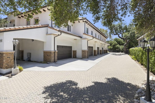 3236 Royal Oaks Dr Unit 5, Thousand Oaks, CA 91362 - view of home's exterior with stucco siding, driveway, stone siding, and a garage
