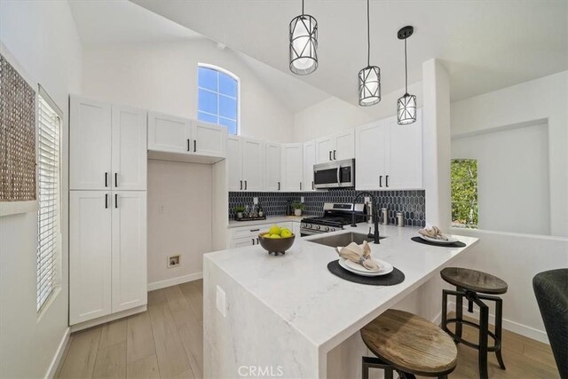7 Montara Dr, Aliso Viejo, CA 92656 - kitchen featuring appliances with stainless steel finishes, a peninsula, high vaulted ceiling, backsplash, and pendant lighting