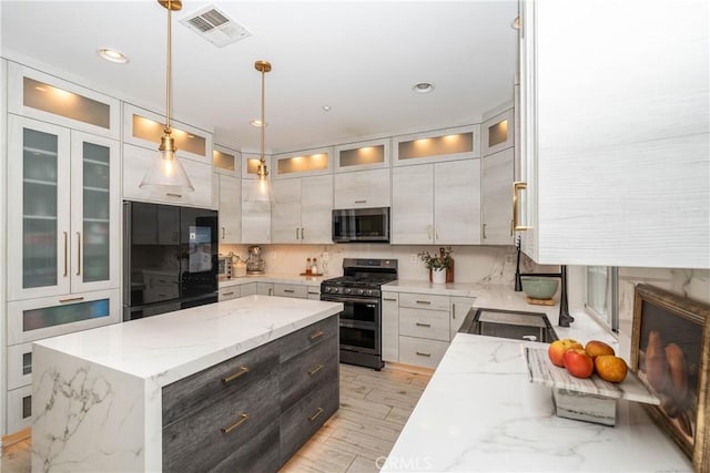 3667 Hawks Dr, Brea, CA 92823 - kitchen with stainless steel appliances, a center island, light stone counters, hanging light fixtures, and glass insert cabinets